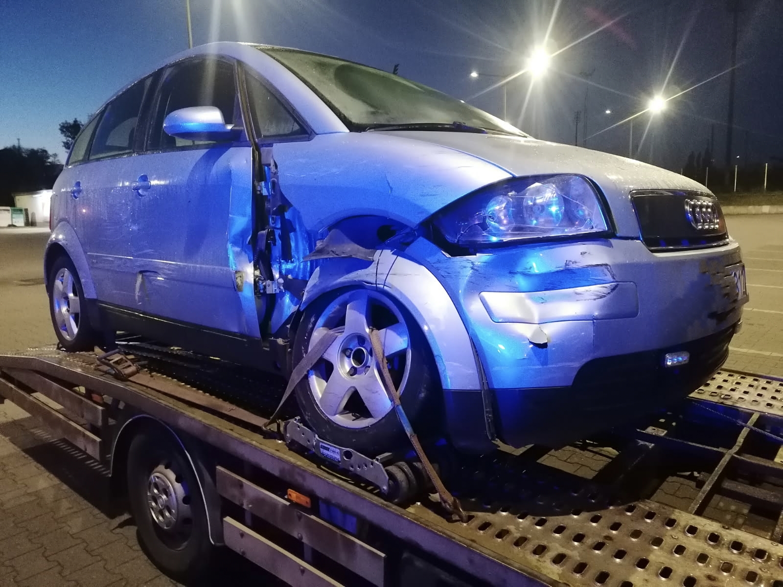 Uszkodzony samochód zabezpieczony na lawecie nocą